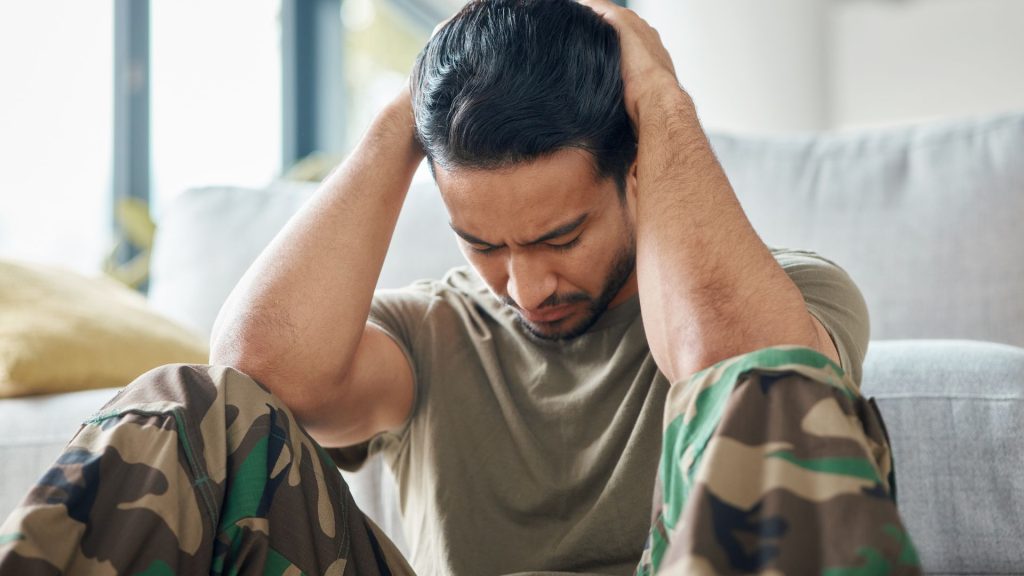 A man sitting with his head in his hands, appearing distressed, symbolizing the emotional struggles of complex trauma and PTSD, highlighting the support services available at Haven Health and Wellness.