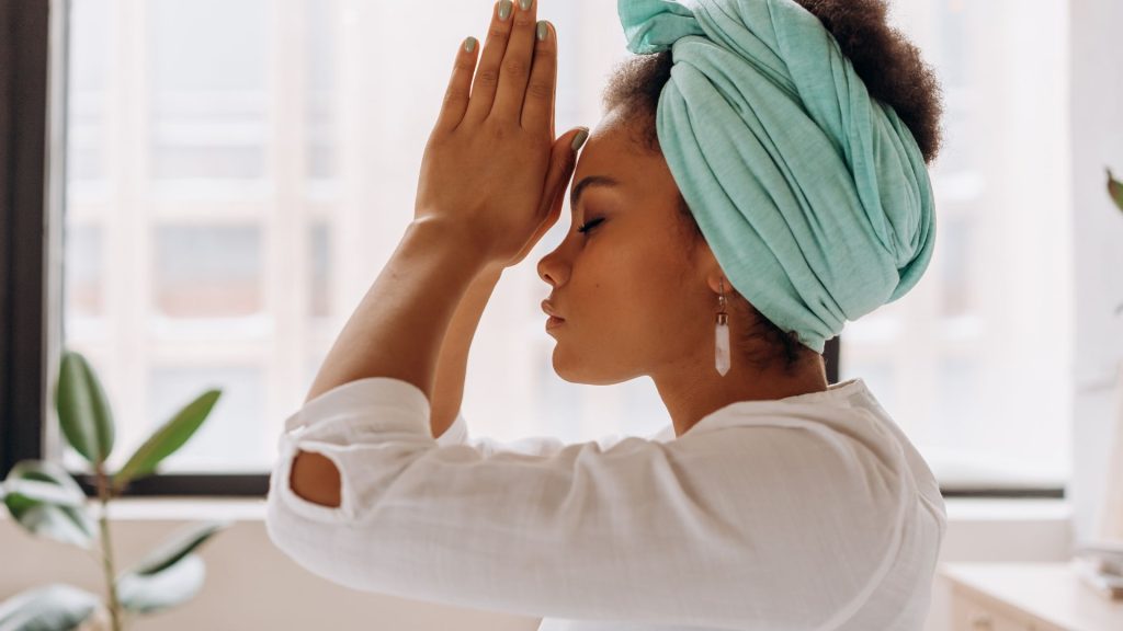 Person practicing mindfulness with hands in prayer pose, symbolizing calm and healing through trauma and PTSD support.