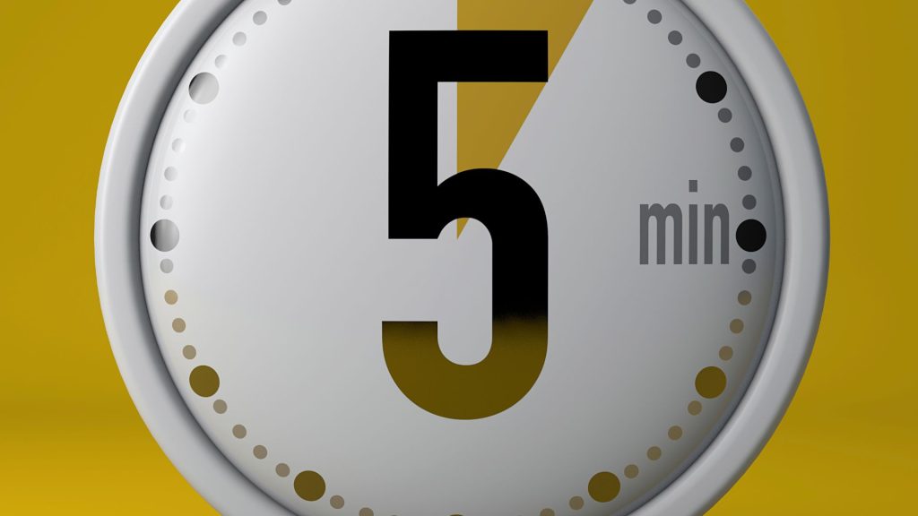 Close-up of a timer set to five minutes on a yellow background, symbolizing the 5 Minute Rule for ADHD and motivation to start tasks.