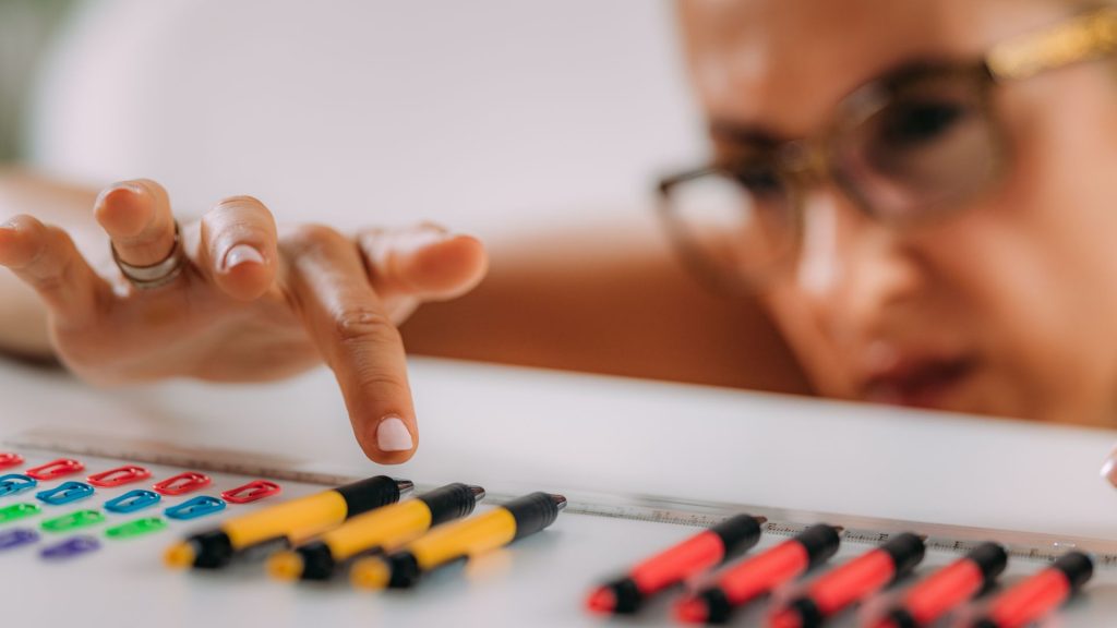 Person aligning pens and paperclips in order, symbolizing AuDHD vs OCD and the difference between focus and compulsion.